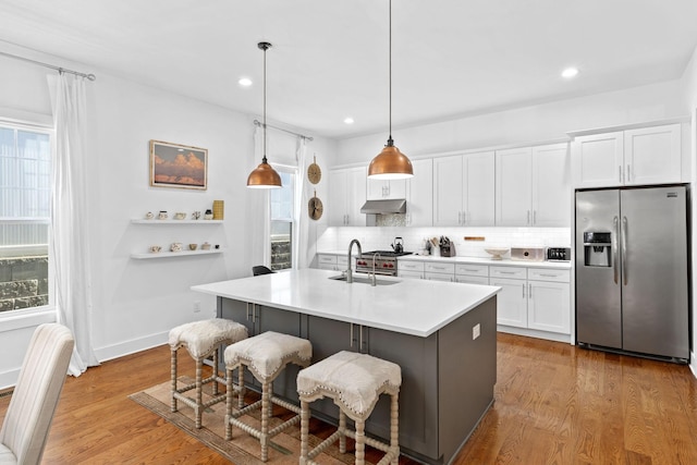 kitchen with plenty of natural light, light wood-style floors, stainless steel refrigerator with ice dispenser, and under cabinet range hood