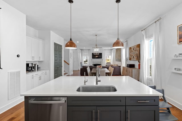 kitchen featuring visible vents, dishwasher, open floor plan, gray cabinets, and a sink