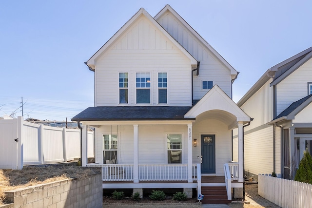 view of front of home with covered porch, fence, board and batten siding, and roof with shingles