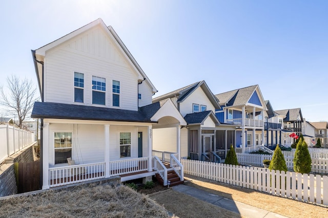 view of front of house with board and batten siding, a residential view, covered porch, and fence private yard