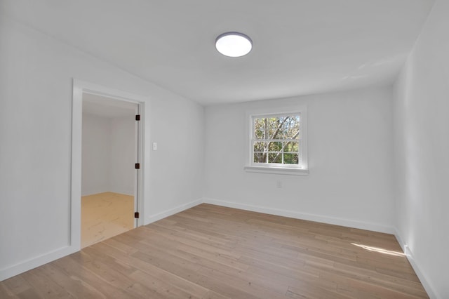 spare room with baseboards and wood finished floors