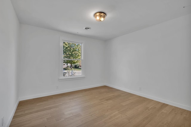 spare room with light wood-style floors, visible vents, and baseboards