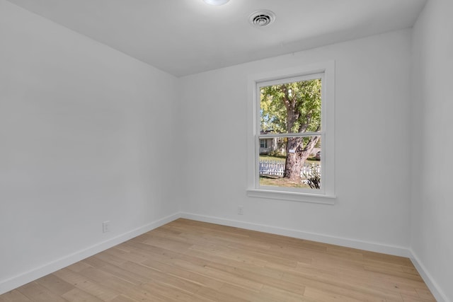 empty room featuring light wood-style floors, baseboards, and visible vents