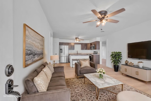 living area featuring light wood-type flooring and a ceiling fan