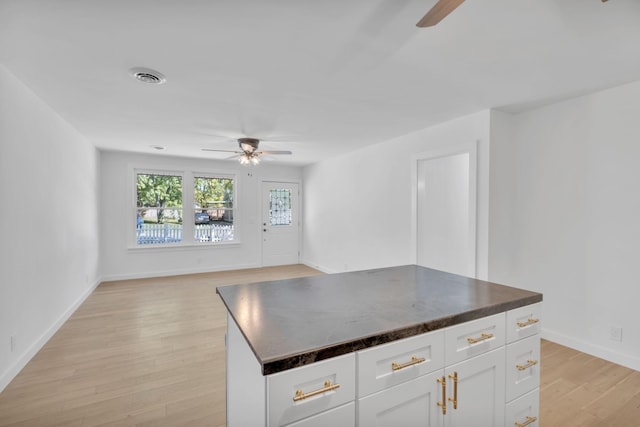 kitchen featuring dark countertops, white cabinets, visible vents, and light wood-style flooring