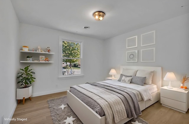 bedroom featuring light wood-style flooring, visible vents, and baseboards