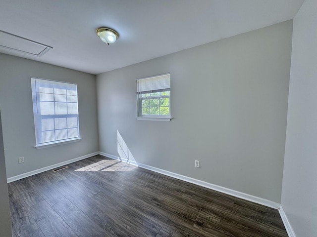 spare room with visible vents, baseboards, and dark wood-style flooring