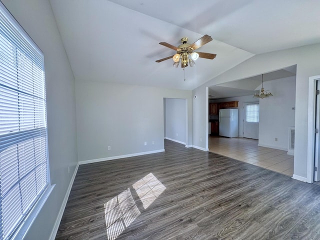 unfurnished living room with lofted ceiling, baseboards, wood finished floors, and ceiling fan with notable chandelier