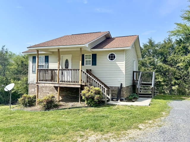 view of front facade with stairs, a shingled roof, and a front yard