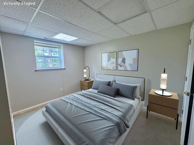 bedroom featuring baseboards, carpet, and a drop ceiling