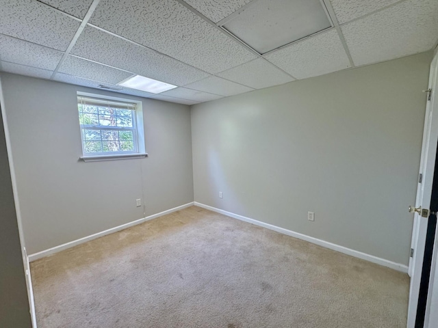 empty room featuring a paneled ceiling, baseboards, and carpet