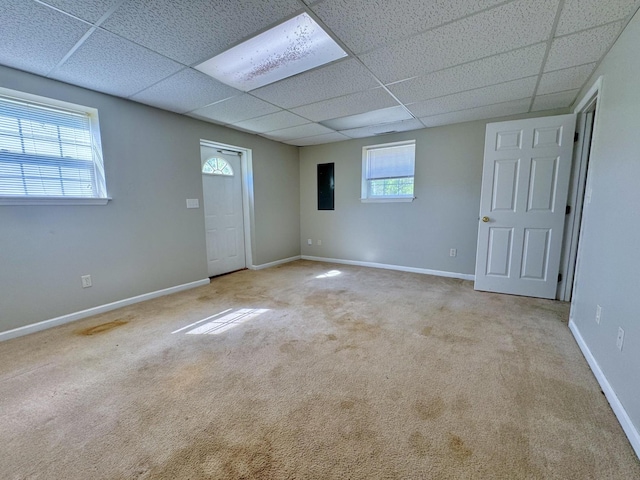 carpeted spare room featuring a paneled ceiling and baseboards