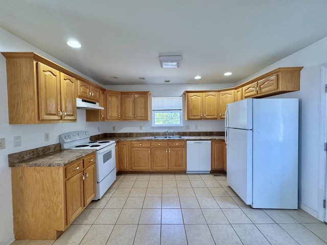 kitchen with dark countertops, a sink, white appliances, light tile patterned floors, and under cabinet range hood