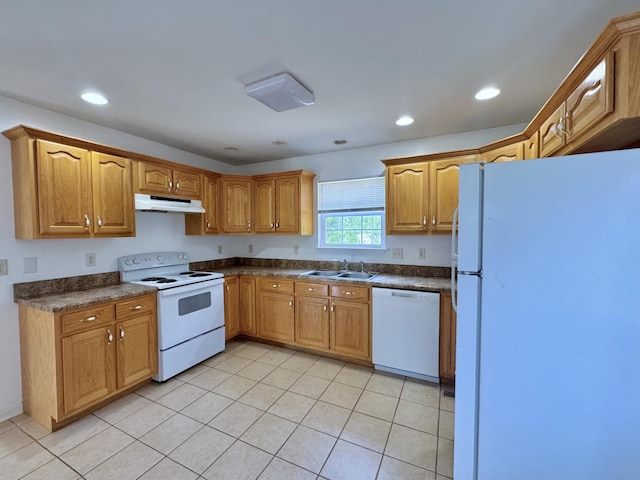 kitchen with dark countertops, a sink, white appliances, light tile patterned floors, and under cabinet range hood