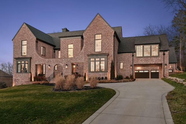 english style home with driveway, a front lawn, and brick siding