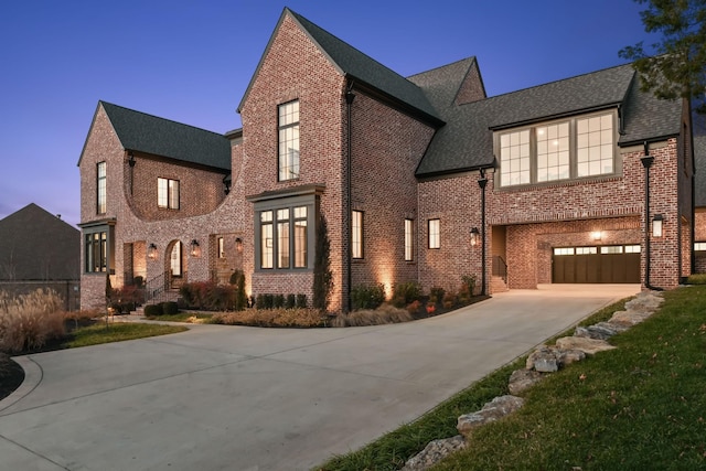 view of front of property with driveway, an attached garage, roof with shingles, and brick siding