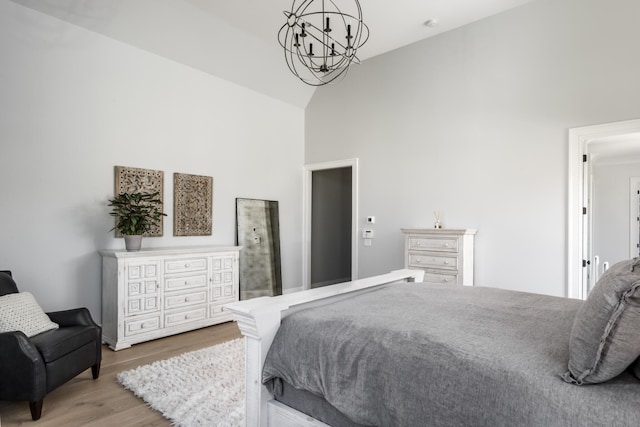 bedroom with high vaulted ceiling, a chandelier, and wood finished floors