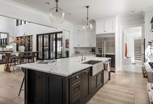 kitchen with white cabinetry, ornamental molding, stainless steel appliances, and a sink