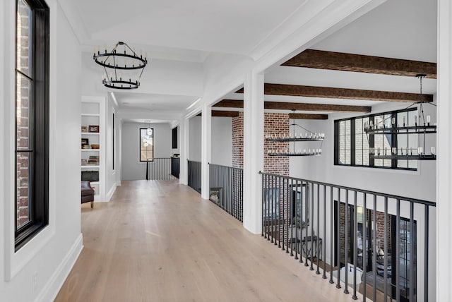 hall featuring a notable chandelier, wood finished floors, an upstairs landing, beam ceiling, and crown molding