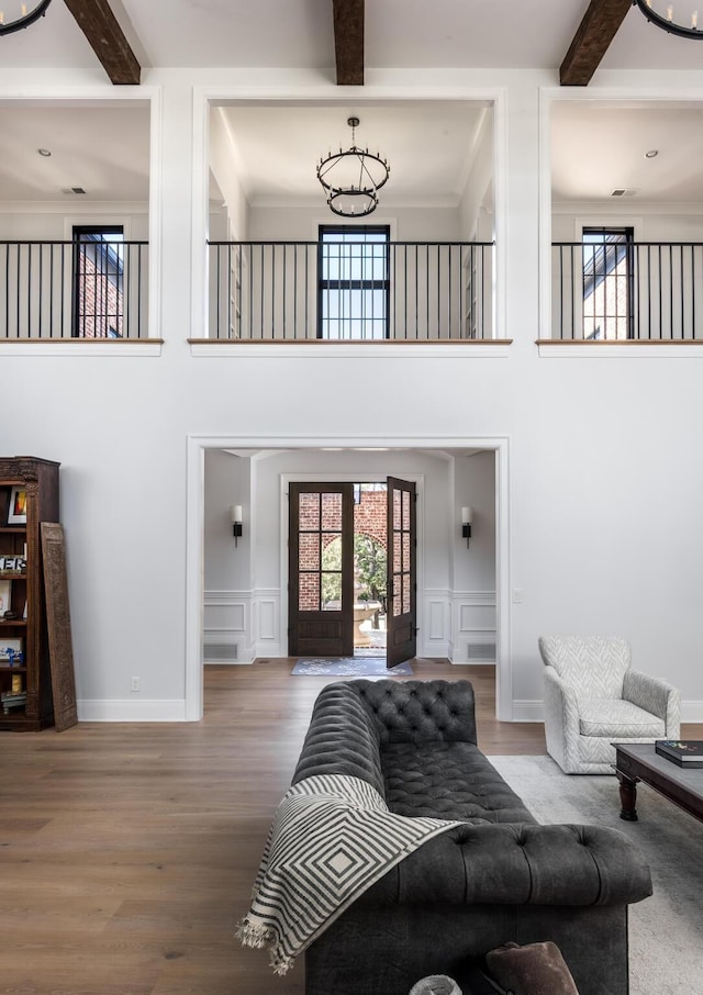 living area featuring a decorative wall, beamed ceiling, and an inviting chandelier