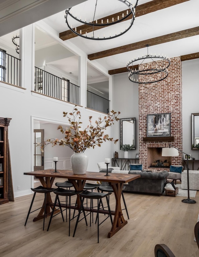 dining area with a chandelier, beamed ceiling, light wood-type flooring, and baseboards