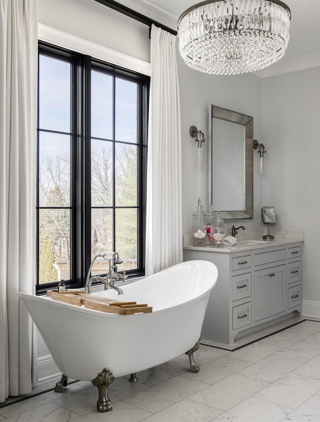 bathroom featuring marble finish floor, crown molding, a soaking tub, and vanity