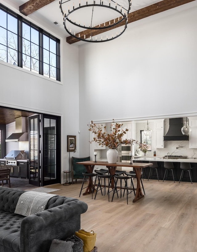 living area with a high ceiling, beam ceiling, and wood finished floors