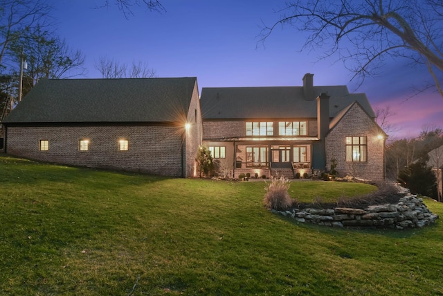 rear view of property with a chimney and a lawn