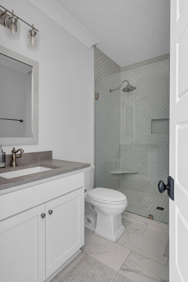 bathroom featuring marble finish floor, a tile shower, vanity, and toilet