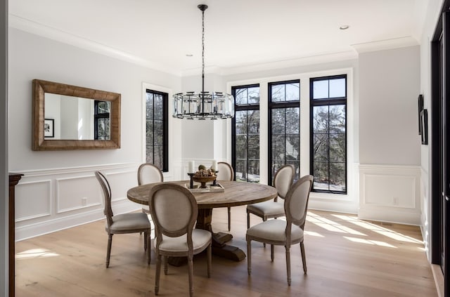 dining area featuring light wood-style floors, a wealth of natural light, ornamental molding, and an inviting chandelier