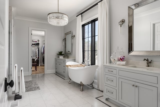 full bathroom with a freestanding tub, a notable chandelier, vanity, marble finish floor, and crown molding