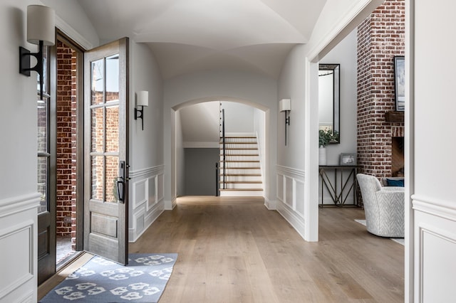 interior space featuring arched walkways, a wainscoted wall, a decorative wall, and wood finished floors