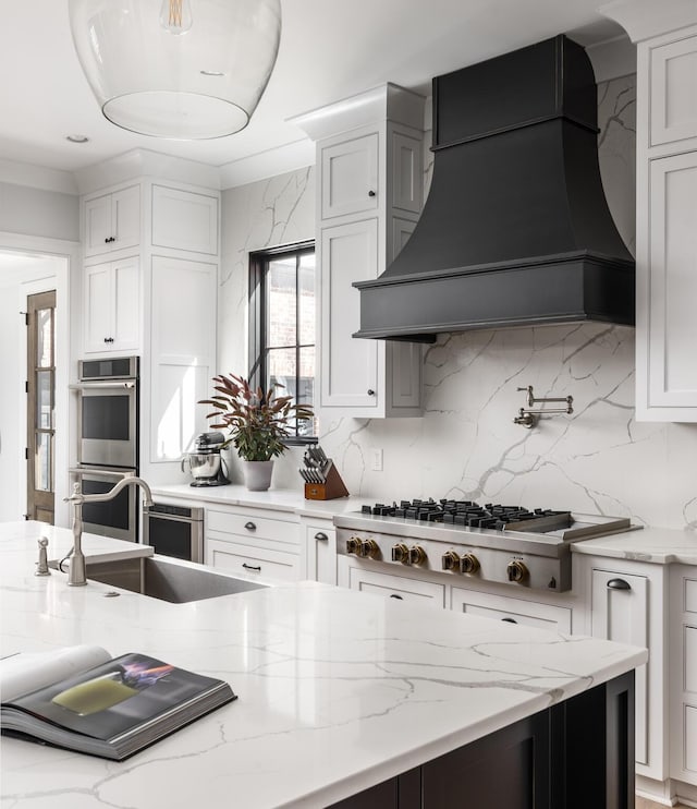 kitchen with appliances with stainless steel finishes, white cabinetry, and custom exhaust hood