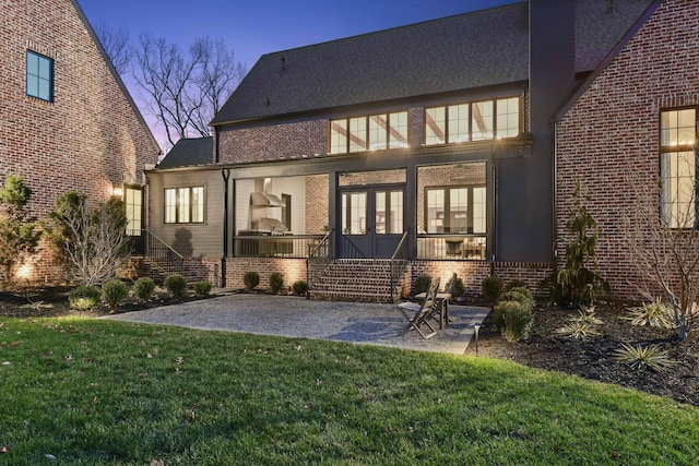 rear view of property featuring a yard, brick siding, and a patio area