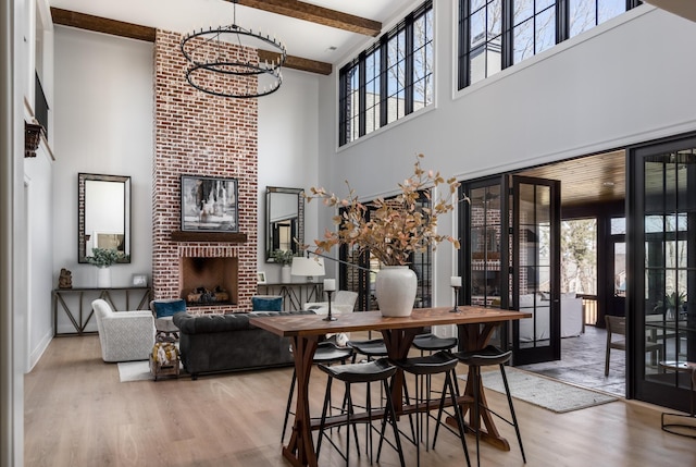 dining room with plenty of natural light, a brick fireplace, wood finished floors, and an inviting chandelier