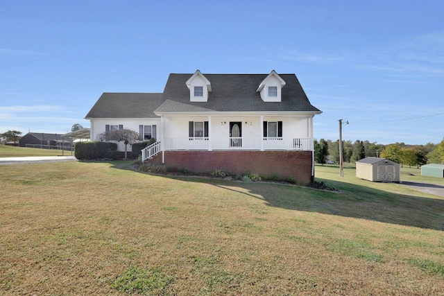 view of front of property featuring a storage shed, covered porch, brick siding, an outdoor structure, and a front lawn