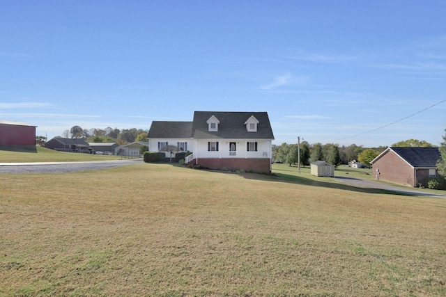 view of front of home featuring an outbuilding, a storage unit, a front lawn, and brick siding