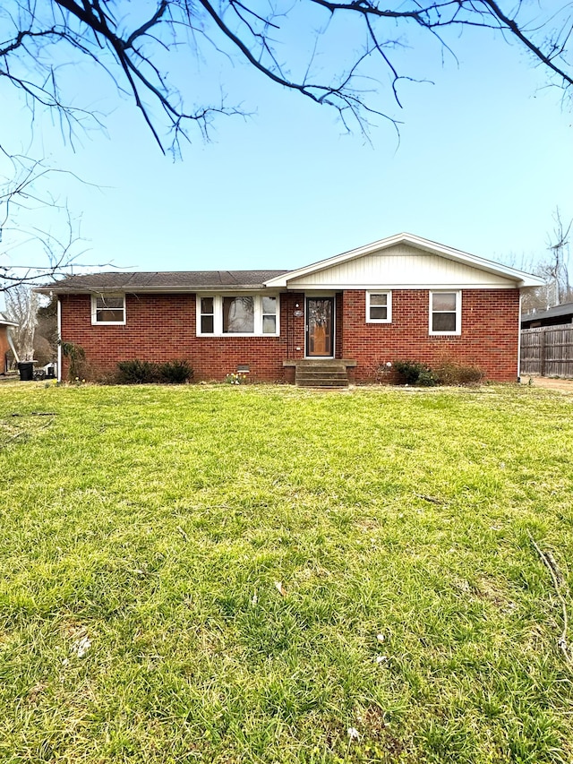 single story home featuring a front yard, brick siding, and fence