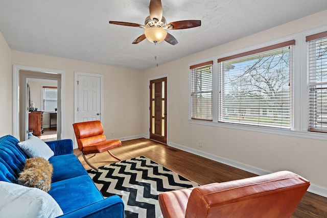 living room featuring a textured ceiling, baseboards, ceiling fan, and wood finished floors