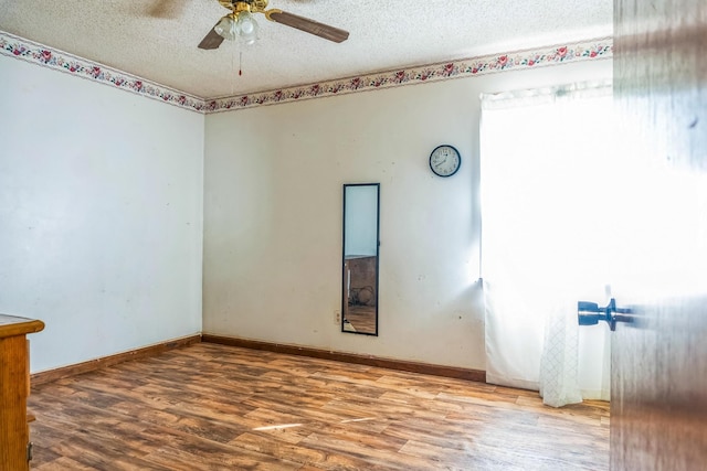 empty room featuring baseboards, a textured ceiling, a ceiling fan, and wood finished floors