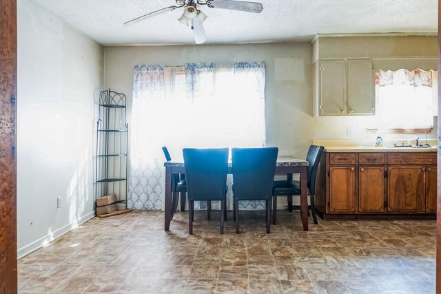 dining room with a textured ceiling, a ceiling fan, and baseboards