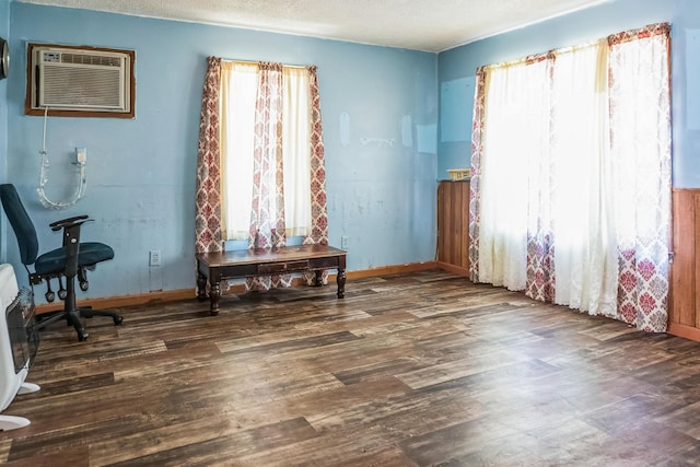 interior space featuring wood finished floors, a textured ceiling, baseboards, and a wall mounted AC