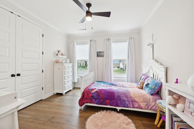 bedroom featuring a ceiling fan, visible vents, ornamental molding, and wood finished floors