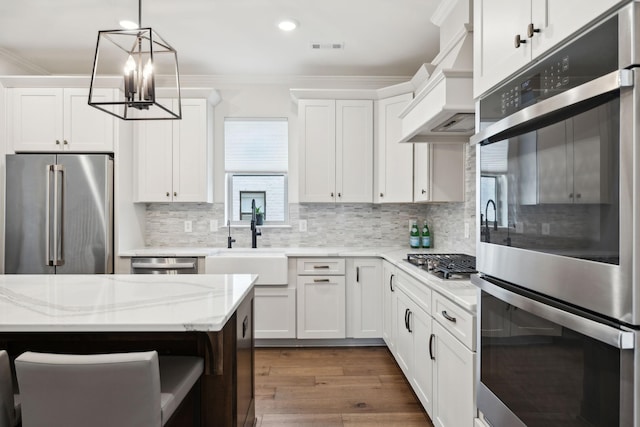 kitchen with appliances with stainless steel finishes, white cabinetry, a sink, and ornamental molding