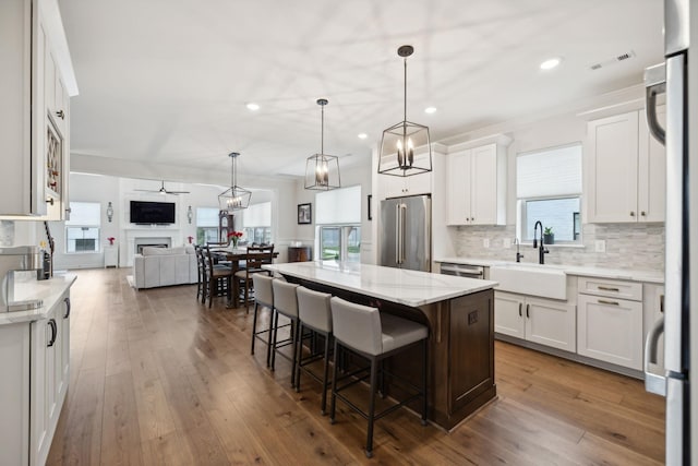 kitchen featuring a breakfast bar, open floor plan, stainless steel appliances, a fireplace, and a sink