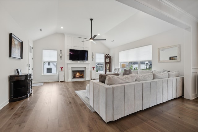 living area with baseboards, dark wood finished floors, ceiling fan, vaulted ceiling, and a fireplace