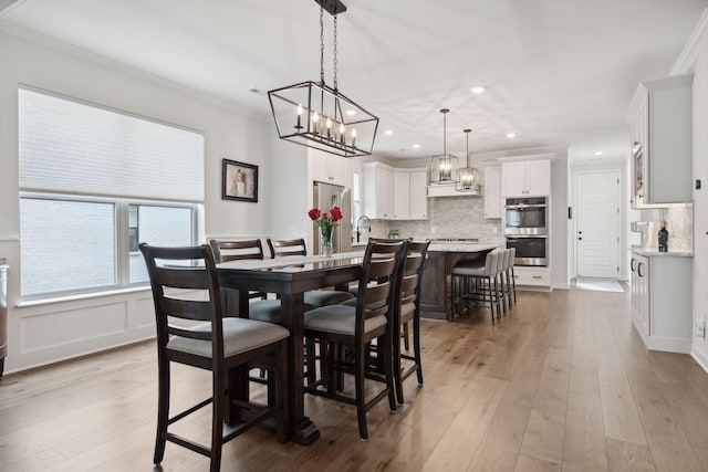 dining space with hardwood / wood-style floors, a decorative wall, recessed lighting, and crown molding