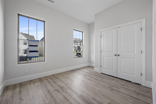 unfurnished bedroom featuring multiple windows, baseboards, and wood finished floors