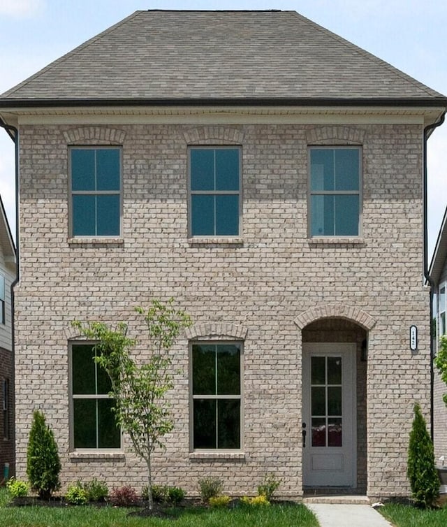 rear view of property featuring brick siding and roof with shingles