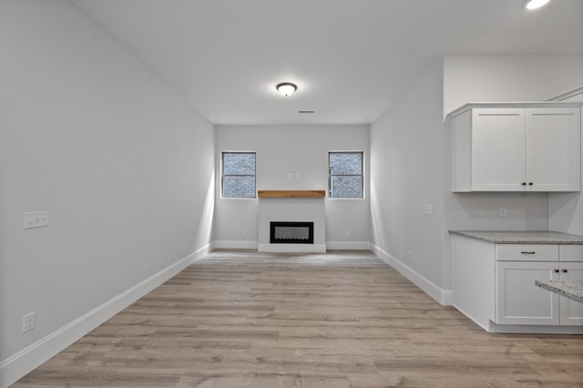 unfurnished living room featuring light wood-type flooring, a fireplace, and baseboards